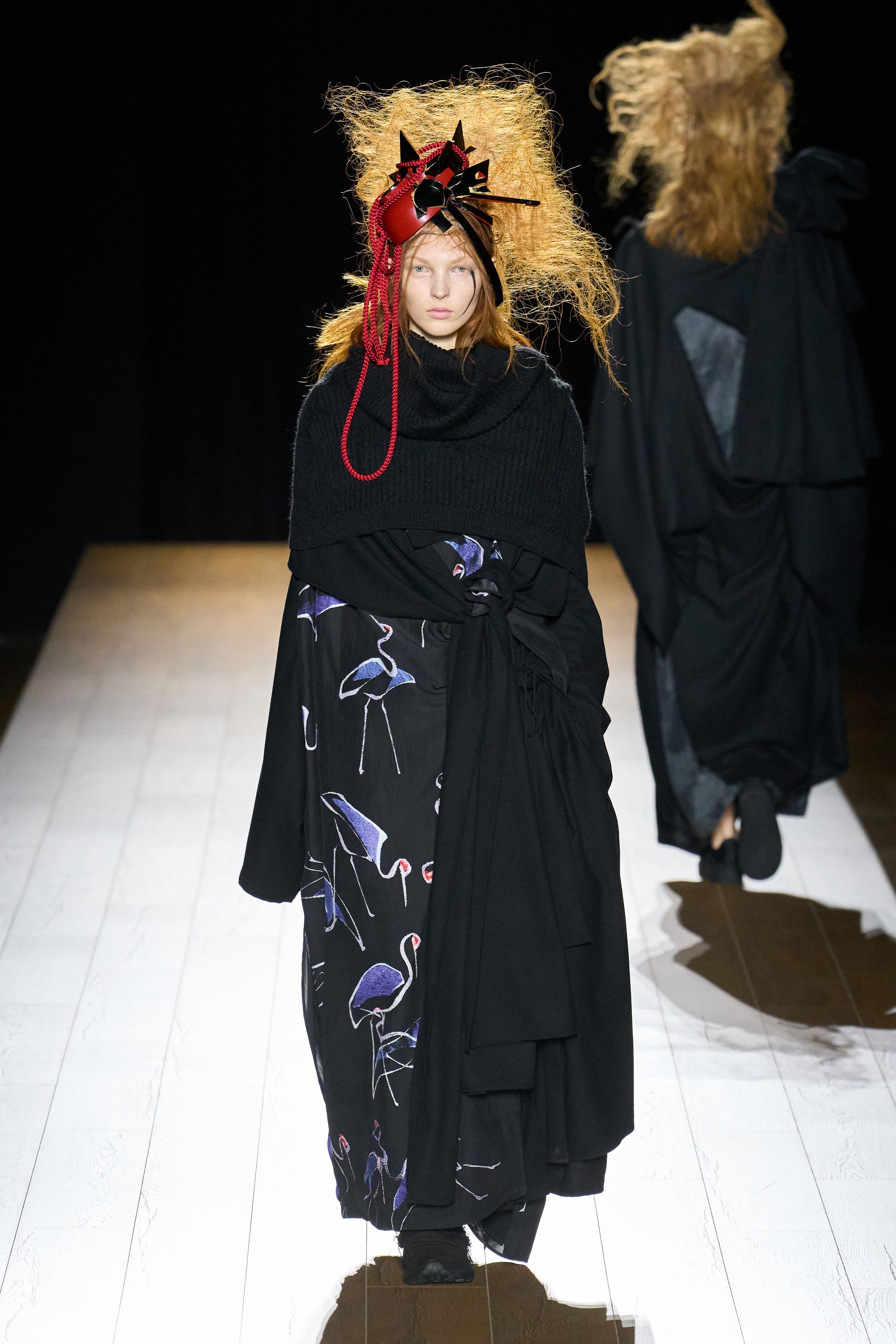 Yohji Yamamoto 本季依然延续标志性的黑色哲学：宽松层叠轮廓、和服式结构与手工拼接面料形成一种诗意而深沉的东方美学。夸张头饰与飘逸衣摆让整场秀像一场黑色戏剧，既神秘又极具艺术感-顽石频道趋势研究